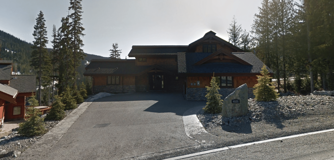 A Google Streetview screen capture showing a stone and brick home from the street. 