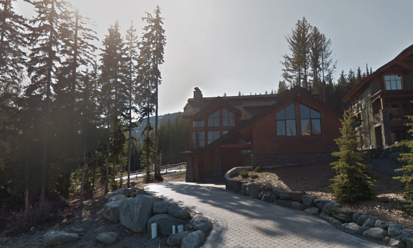 A Google Streetview screen capture showing a stone and brick home from the street. 