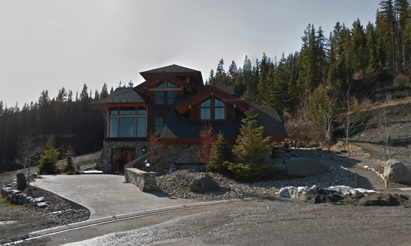 A Google Streetview screen capture showing a stone and wood home from the street. 