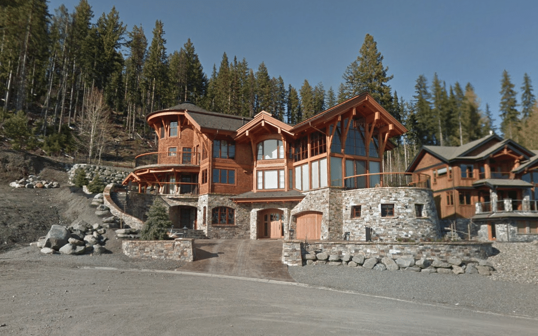 A Google Streetview screen capture showing a stone, brick and wood home from the street. 