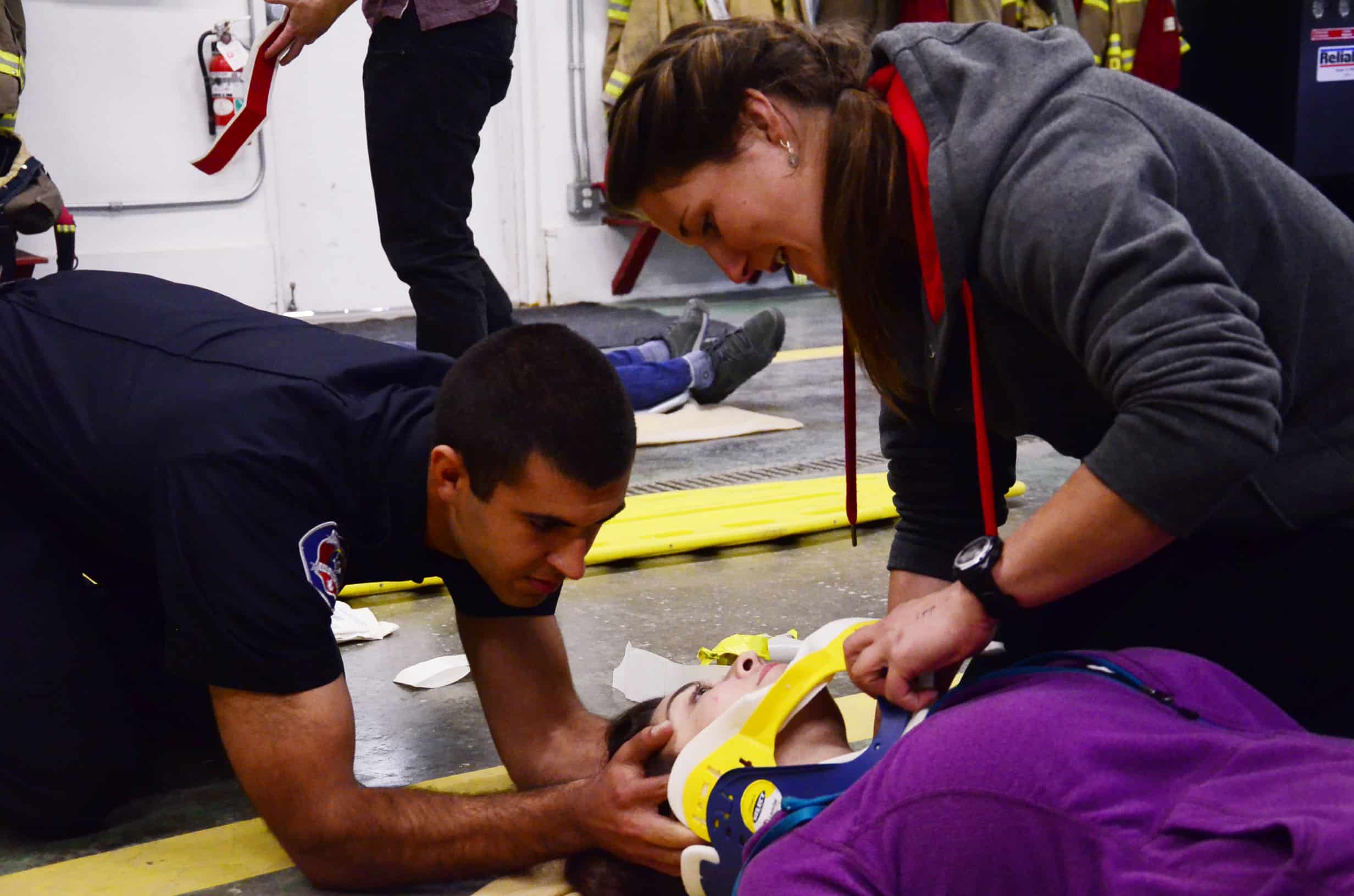 Kyle Labonte supports acting patient Gemma Harris' head while Emily Perrins adjusts the neck brace.