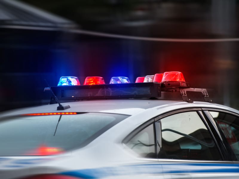 A stock photo of a police car with flashing red and blue lights.