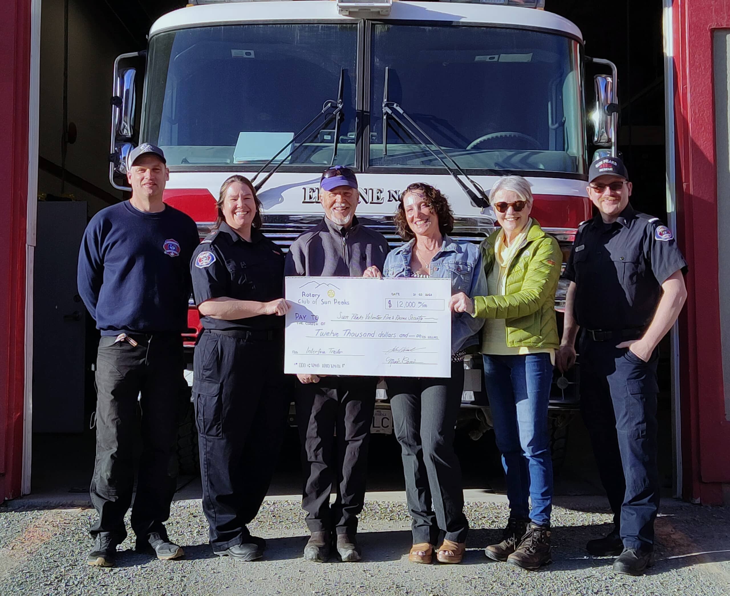 Members of the Rotary Club stand alongside SPVFRS volunteers, holding an oversized cheque for $12,000.