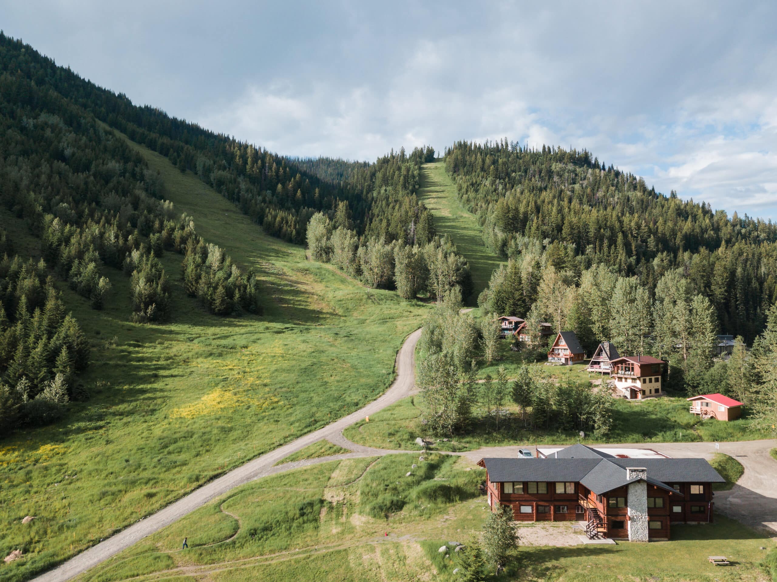 An aerial view of buildings and green grass with sloping mountains. 