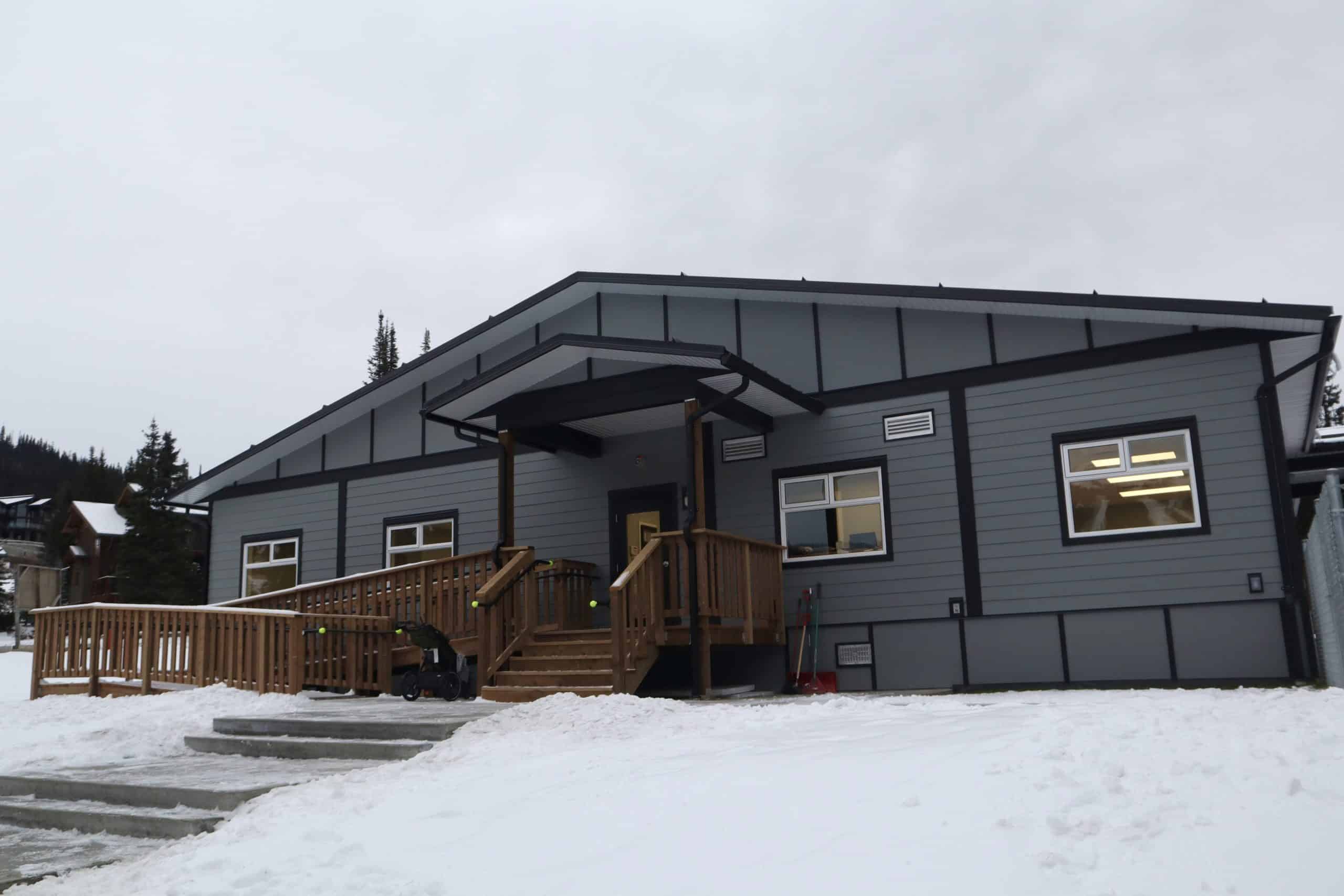 A grey building with a brown deck.