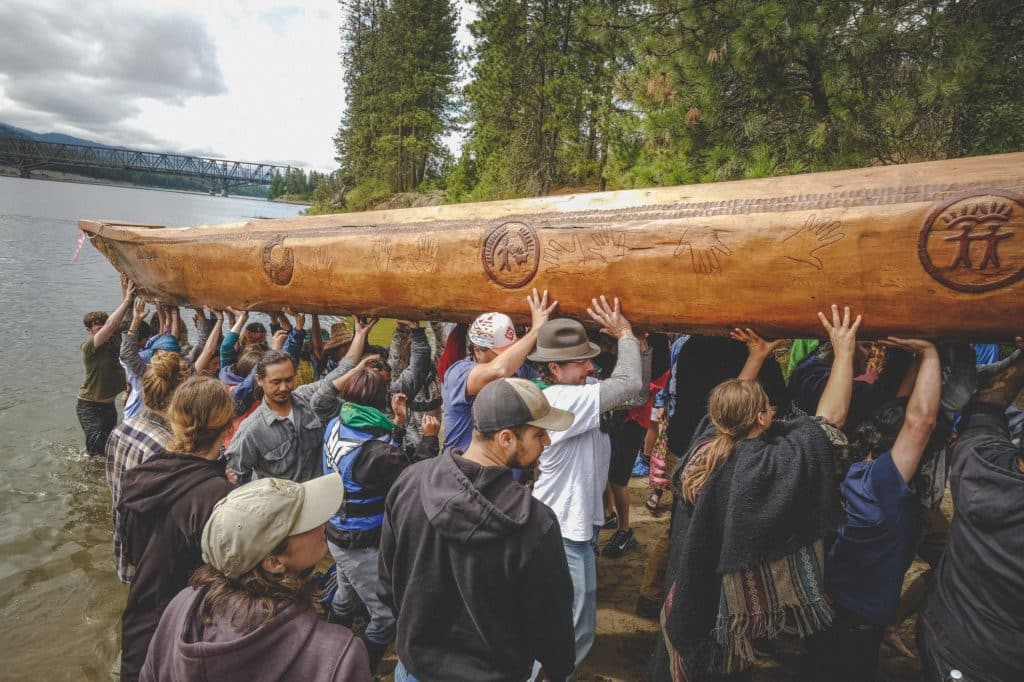 Sx̌ʷnítkʷ Canoe Journey participants help in hauling one of the hand carved canoes out of the water at the end of a journey leg. Photo provided by Sx̌ʷnítkʷ Canoe Journey