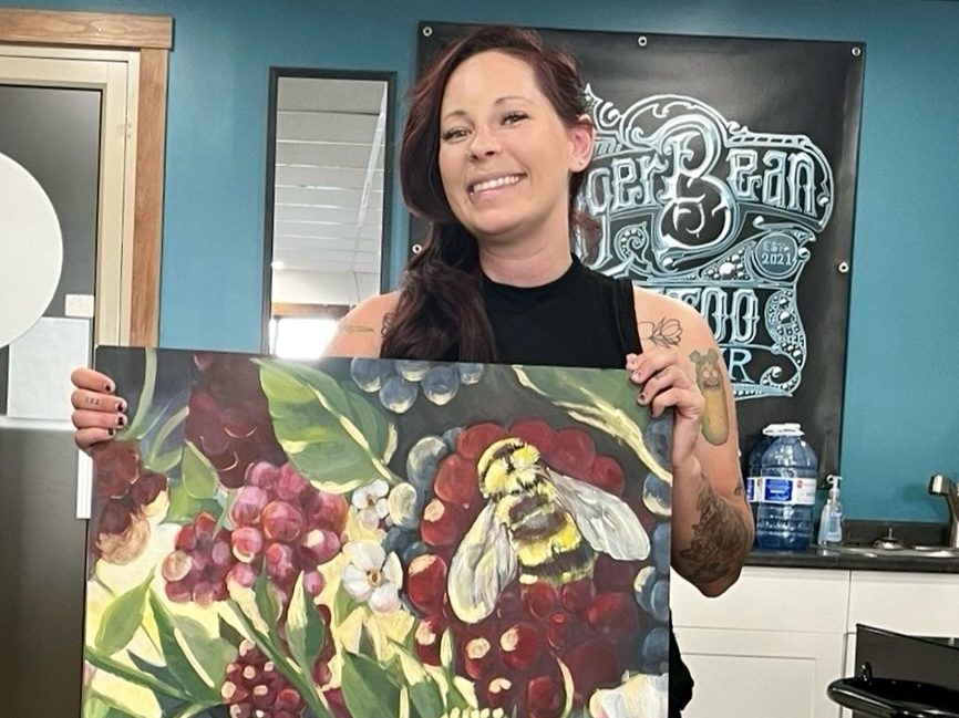 Amie Easton with her painting Garden Time in JuggerBean Tattoo Parlour, Sun Peaks.